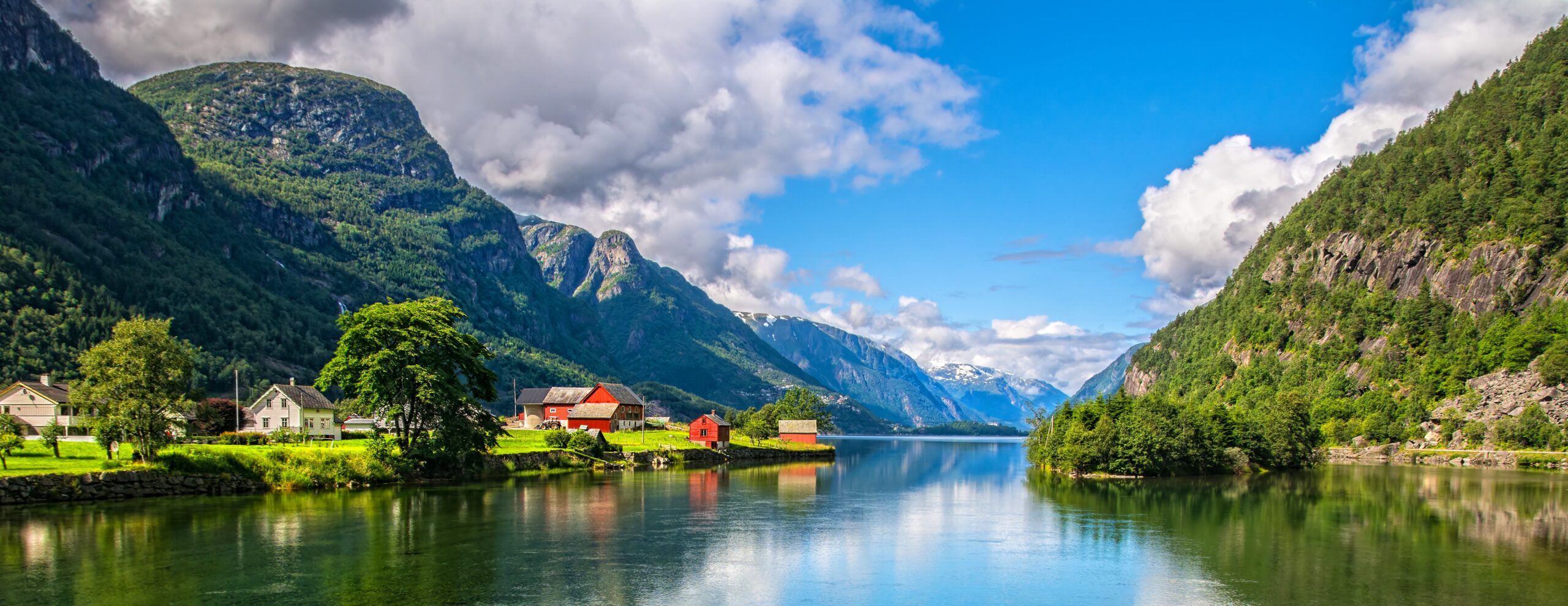 Norwegian fjord landscape with mountains, calm reflective water and countryside houses in the Scandinavian mountains